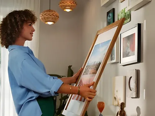 Vrouw hangt een lijst op in een gezellig ingericht huurhuis