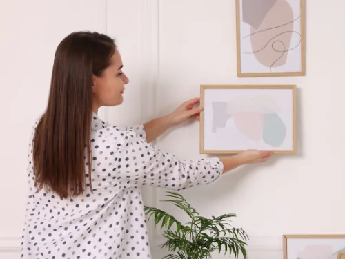 Vrouw zet fotolijsten uit op de muur