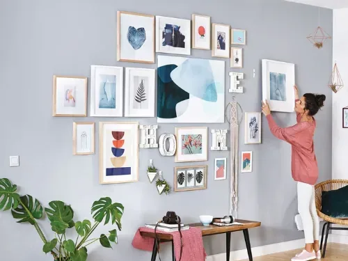 Vrouw hangt lijsten op voor een kleurrijke salonwand