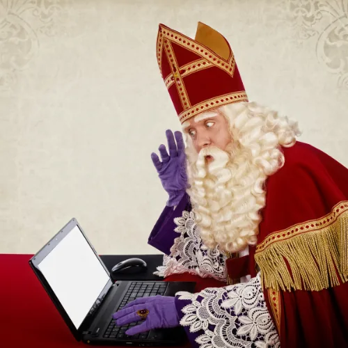 Sinterklaas kijkt verrast naar zijn laptop