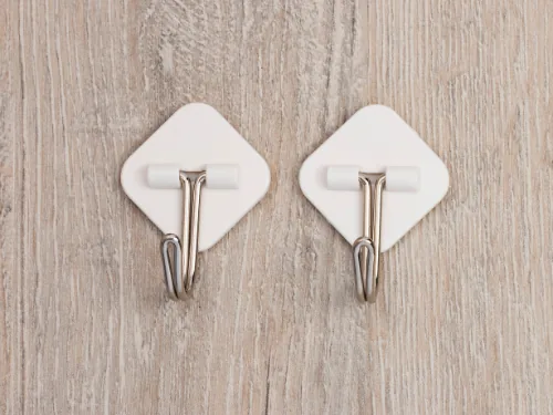 Twee zelfklevende haakjes op een houten wand