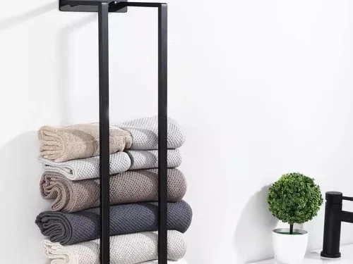 Zwart handdoekrek met opgerolde handdoeken naast de wastafel